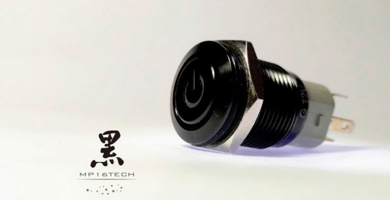 圖片隸屬於"黑色金屬外殼LED防水按鈕開關 極致黑潮 | 鉑達"文章，說明外殼材質不同 但功能相同。圖片為1顆特寫的鋁氧化黑金屬按鈕開關，顯示氧化黑金屬開關與不鏽鋼防水按鈕的規格尺寸都相同。氧化黑金屬按鈕開關只有變更外觀顏色，功能尺寸都相同，經過氧化陽極處理，金屬開關換上一身黝黑的膚色，多了黑色的外觀，黑殼的金屬按鈕。